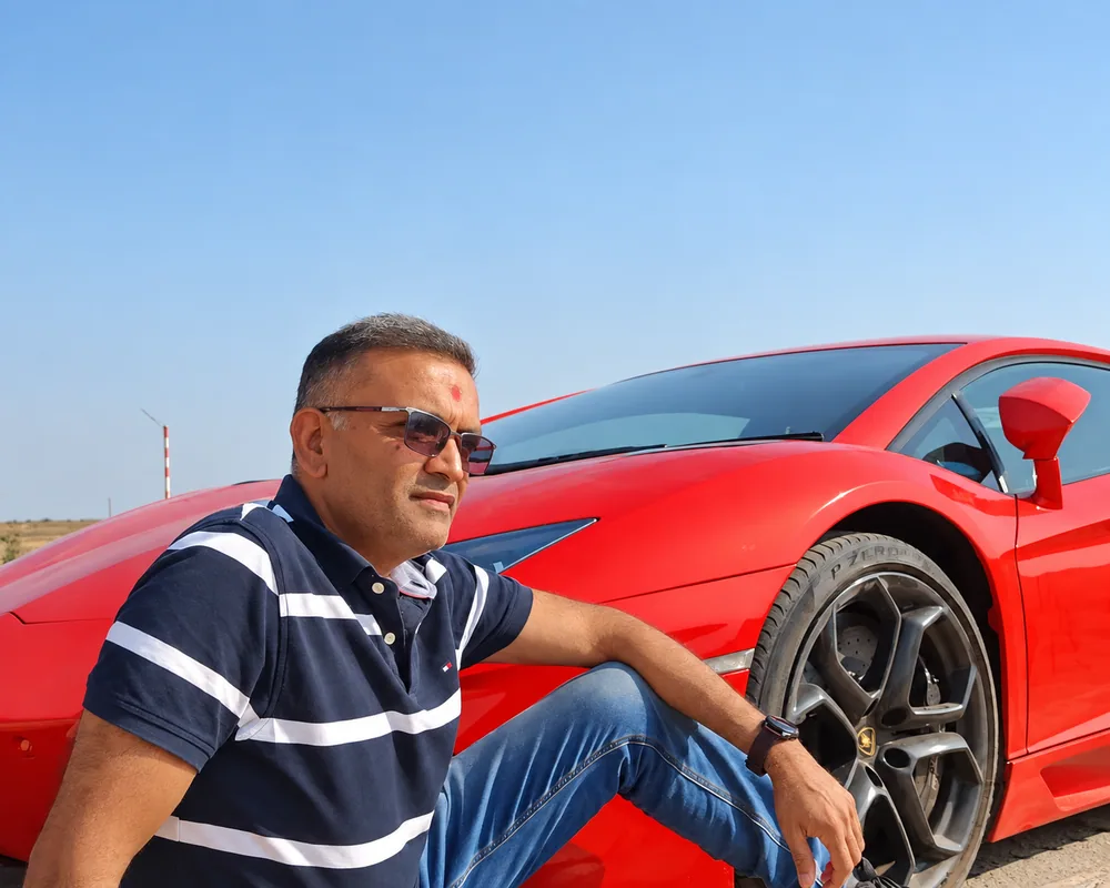 Motor Driving Guru instructor seated beside a red sports car