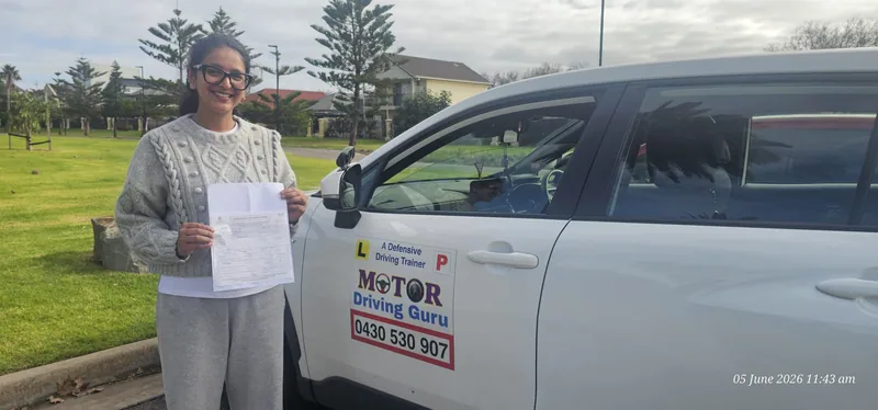 Learner in a grey jumper holding a certificate beside the school car