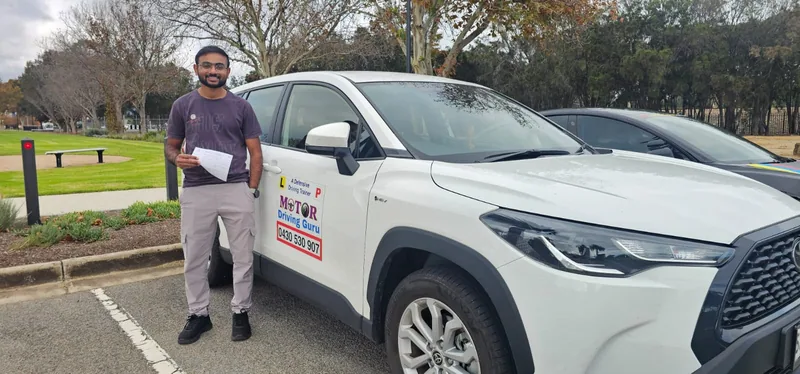 Learner in a purple shirt standing beside the Motor Driving Guru SUV